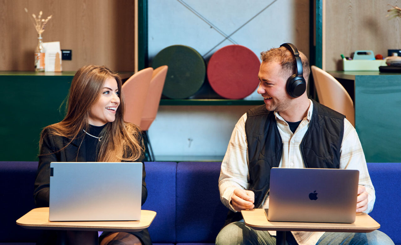 Man en vrouw kijken elkaar lachend aan achter laptop
