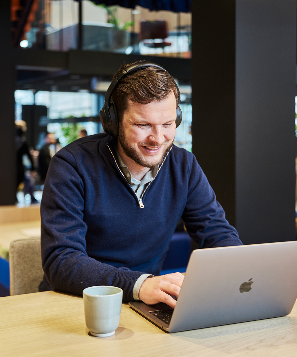 Man zit lachend met koptelefoon achter laptop