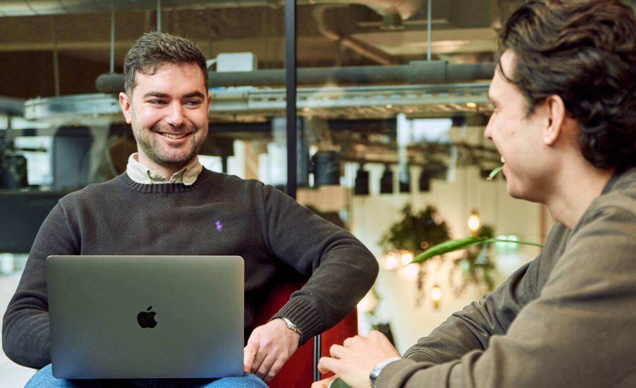 Jongen zit lachend achter zijn laptop