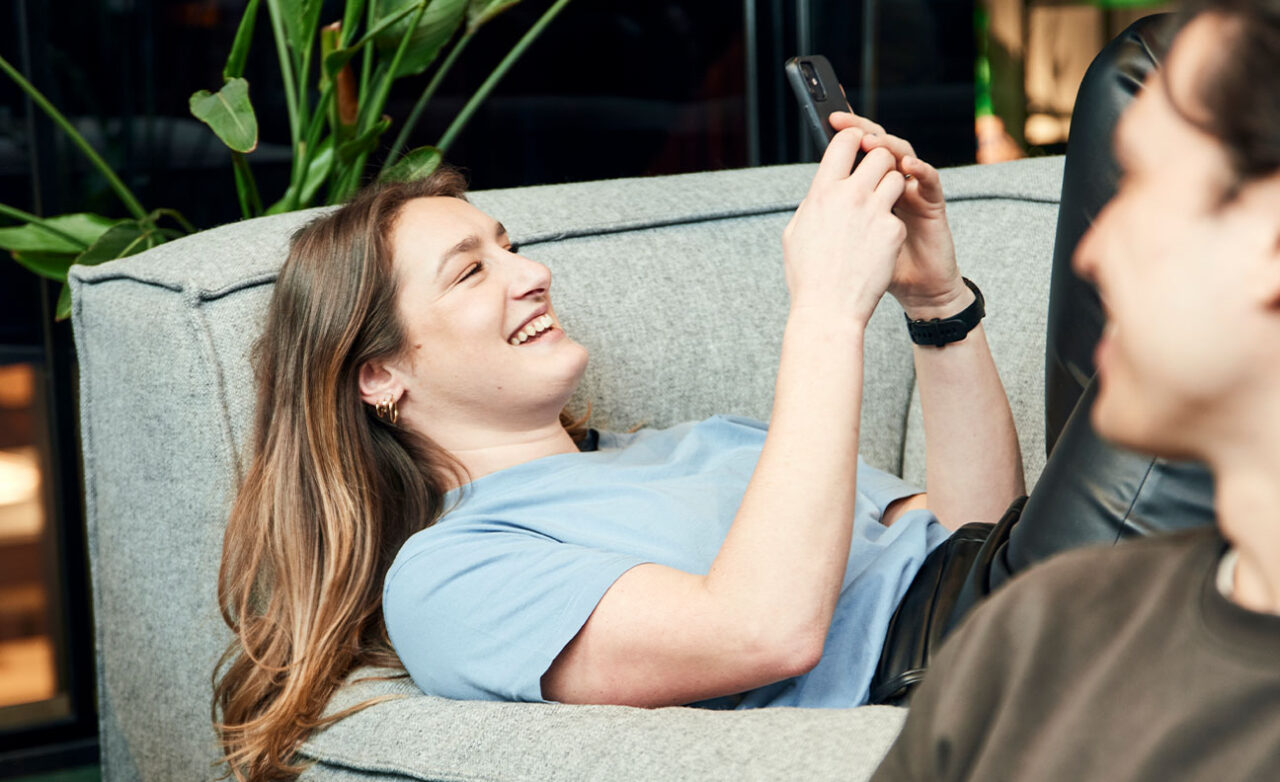 Vrouw kijkt lachend op mobiel
