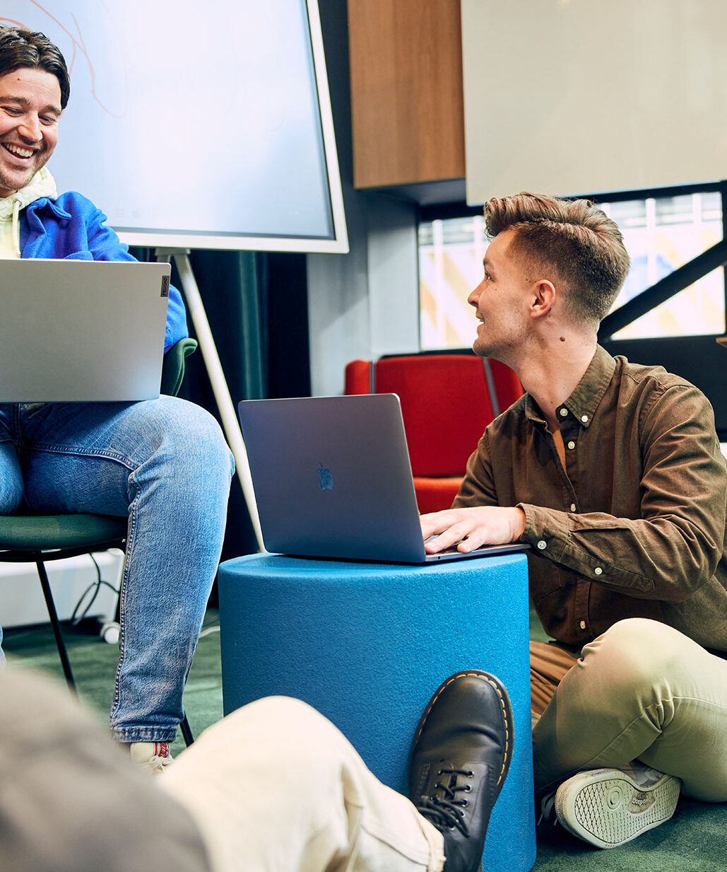 Mannen zitten te lachen achter laptop