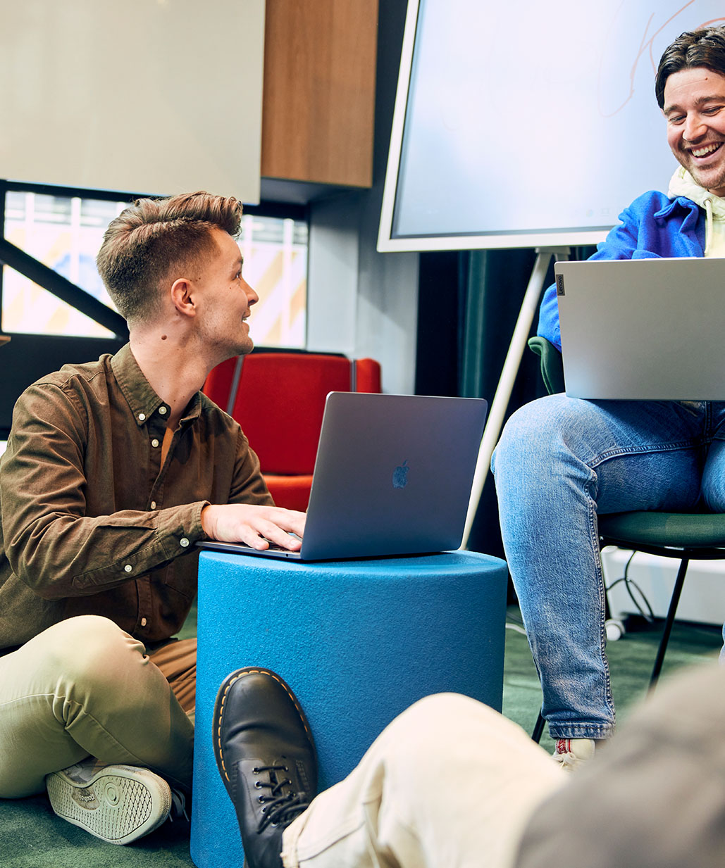Mannen zitten te lachen achter laptop