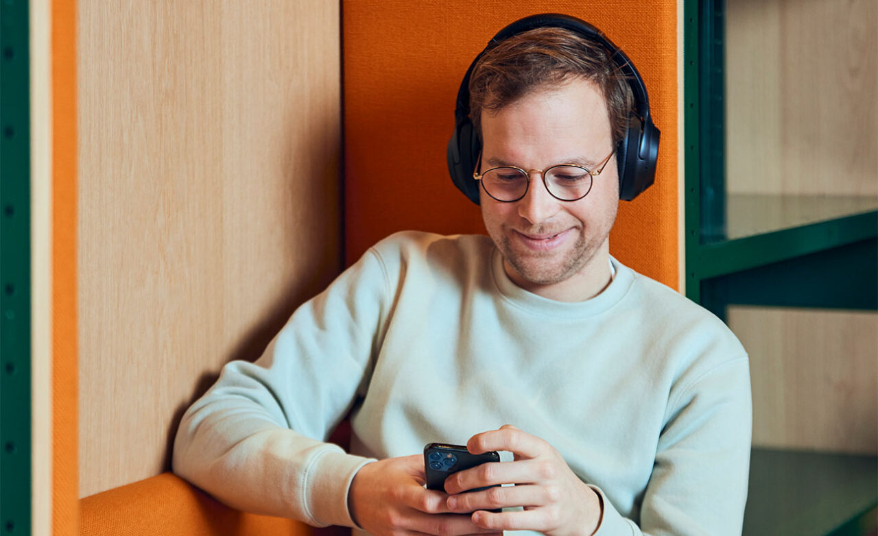 Man zit met koptelefoon op mobiel