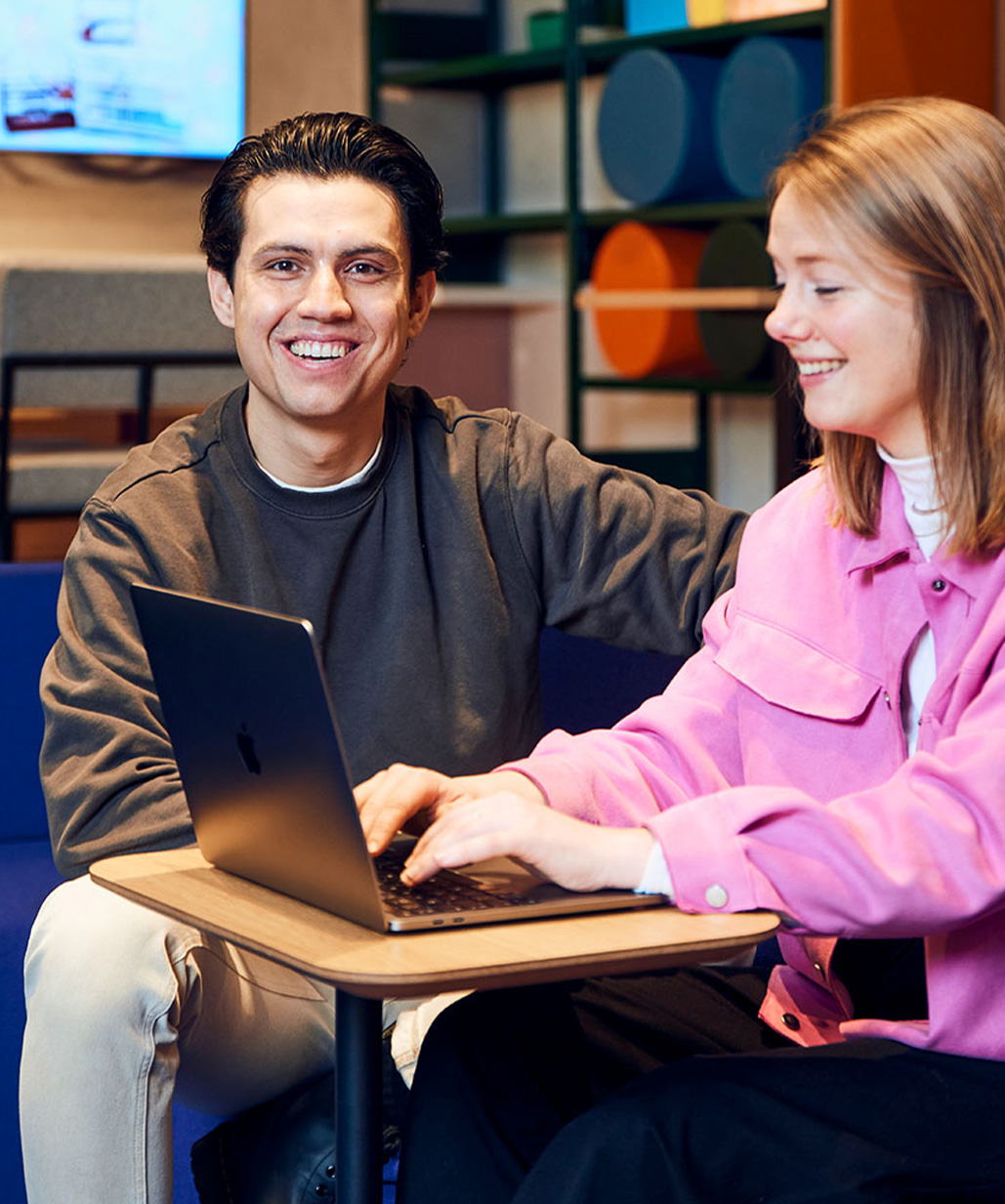 Man en vrouw zitten te lachen achter laptop