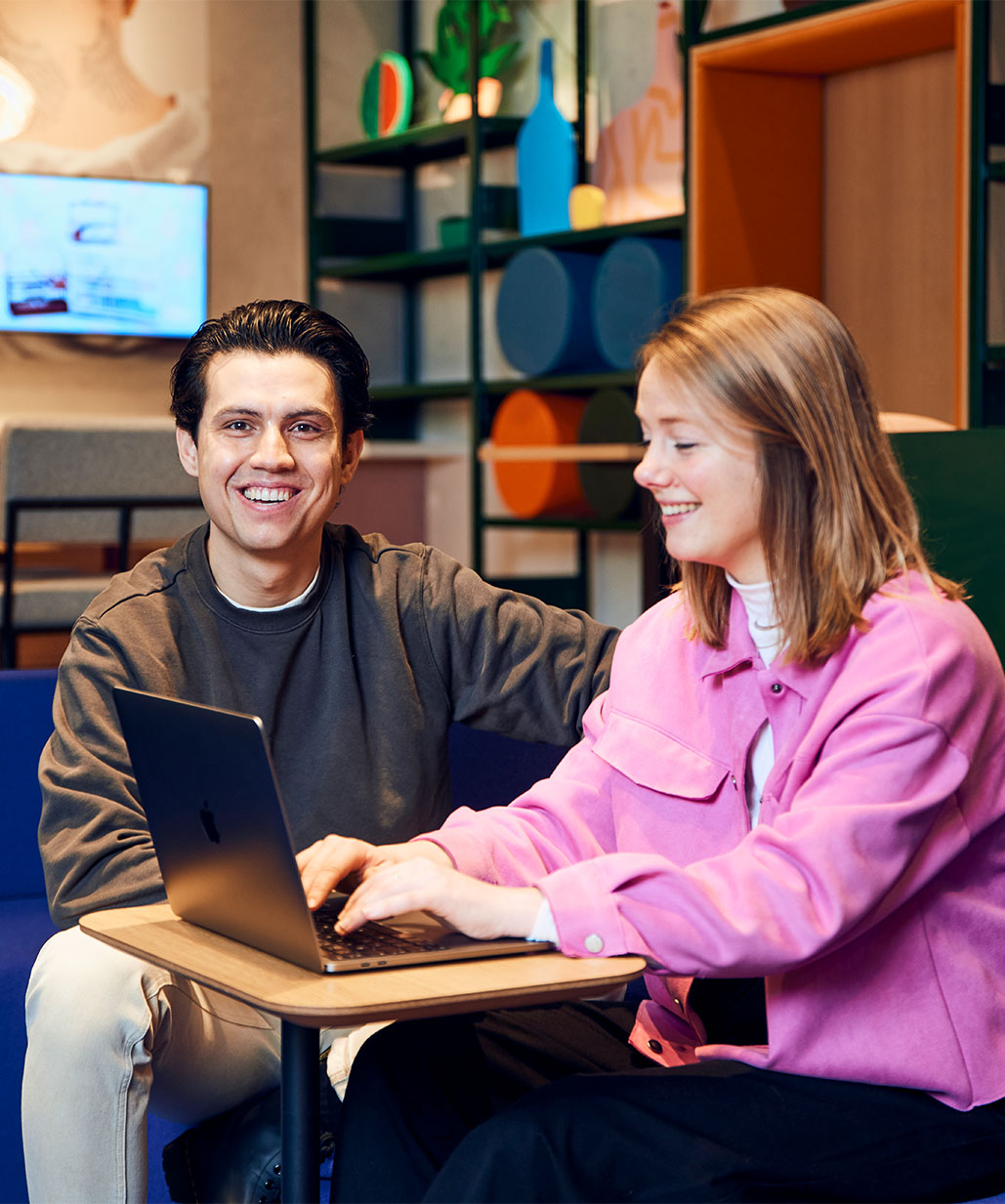 Man en vrouw zitten te lachen achter laptop