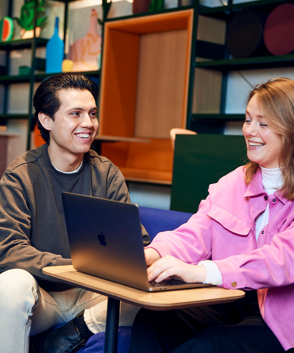 Collega's lachen met elkaar achter laptop