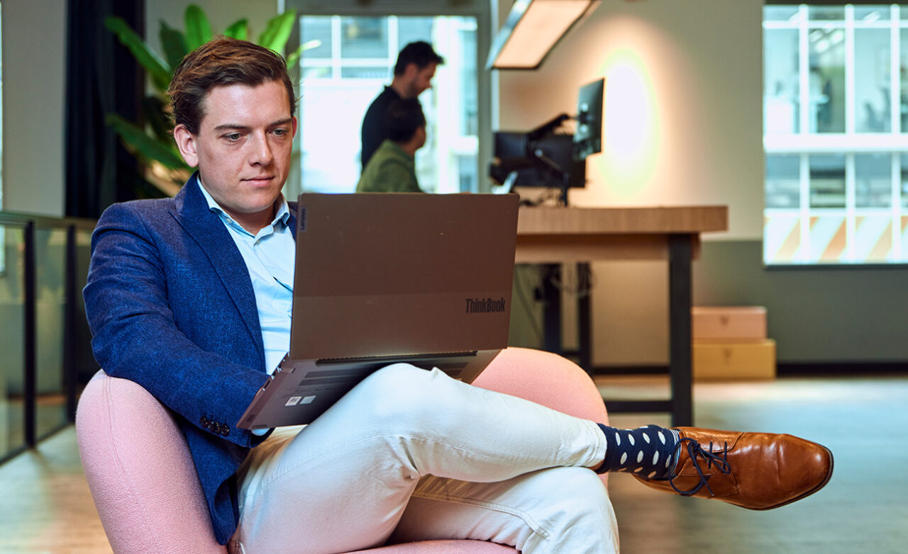 Man zit in loungestoel achter laptop