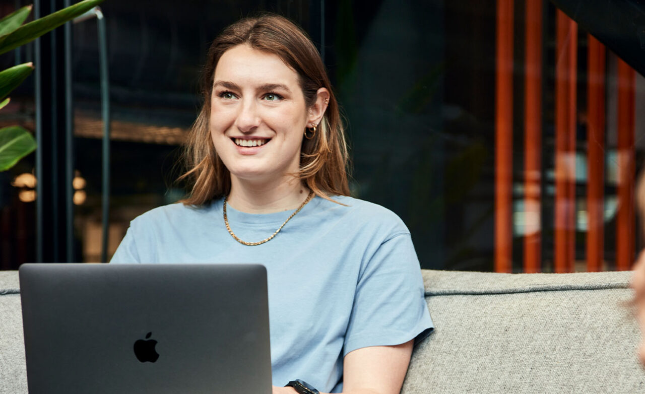 Vrouw kijkt lachend weg van laptop