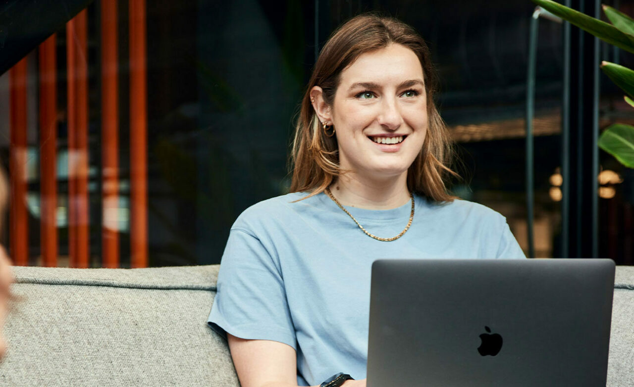 Vrouw kijkt lachend weg van laptop