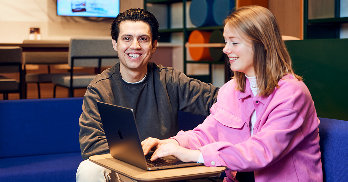Man en vrouw zitten te lachen achter laptop