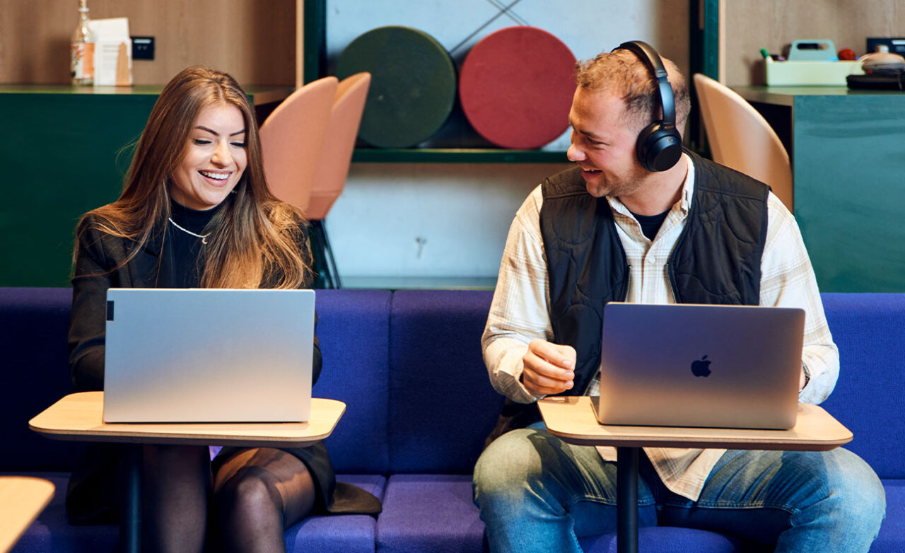 Jongen en meisje lachen achter laptop